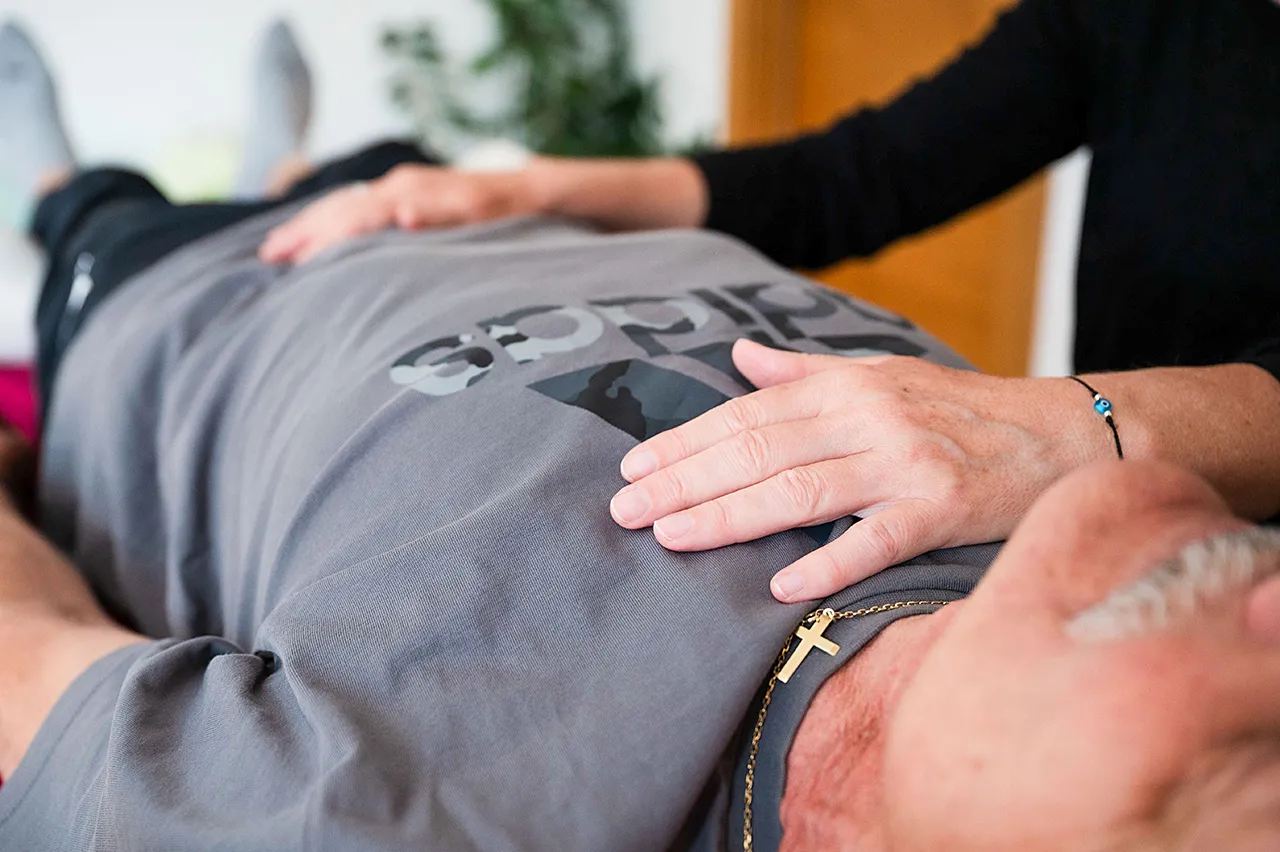 _DSC7568-1 Cranio-Sacral-Therapie – Mann wird von Therapeutin sanft am Bauch berührt.