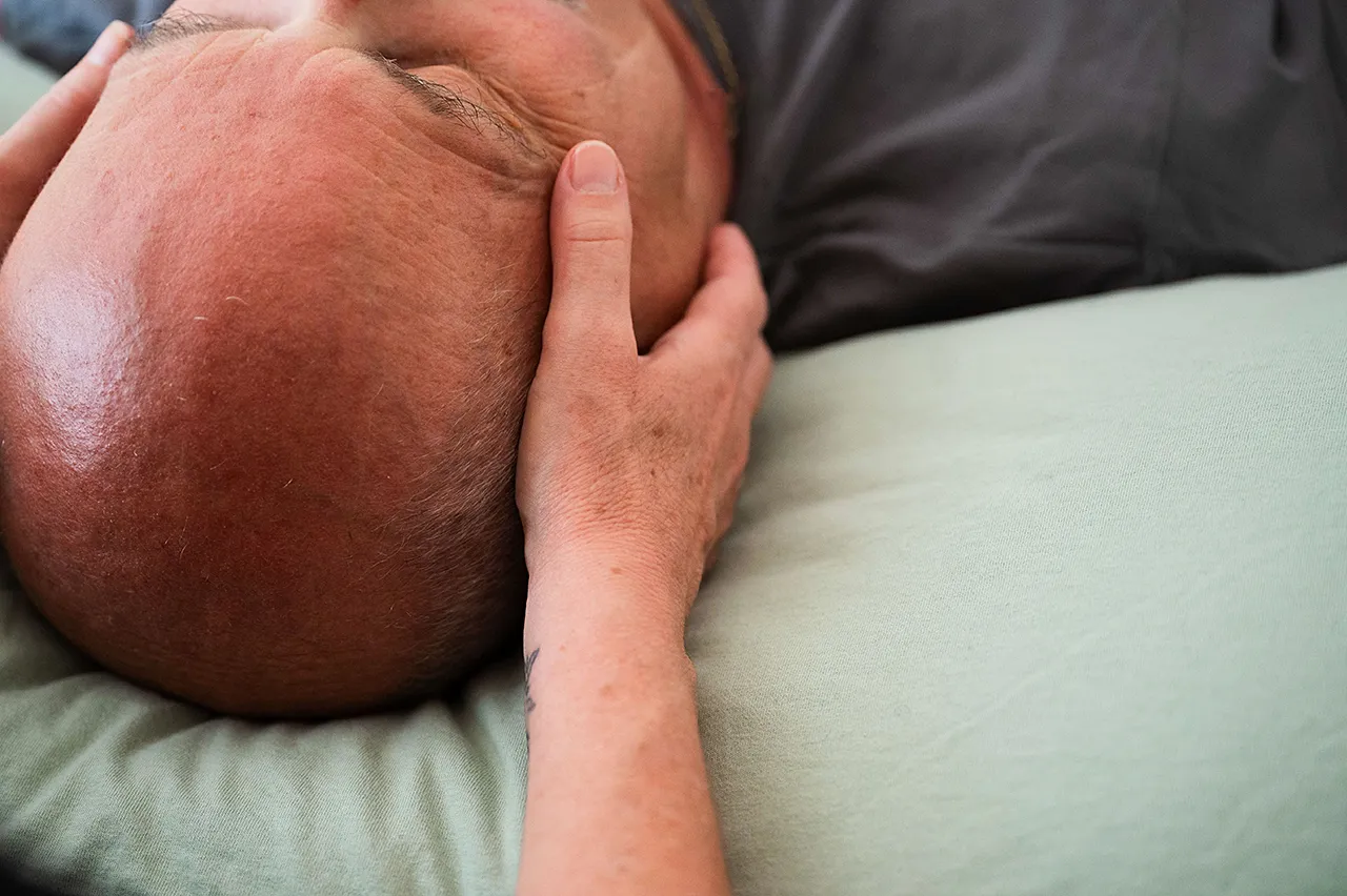 _DSC7598-1 Cranio-Sacral-Therapie – Mann wird von Therapeutin sanft am Kopf berührt.